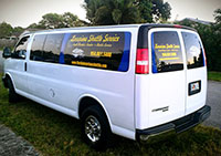 A white van with blue and yellow lettering parked in the grass.