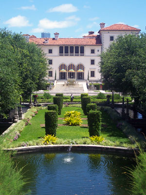 A large garden with bushes and trees in front of it.